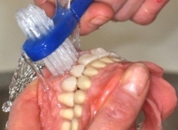 Kuva: Irrotettavan hammasproteesin puhdistaminen erityisellä harjalla